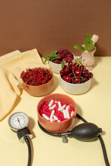 Red fruits of currants, raspberries and cherries in bowls against pills. Health concept. Blood pressure