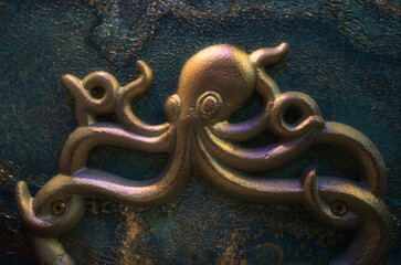 Close-up of a sculpted brass octopus on moody blue wallpaper—an artistic, nautical accent perfect...
