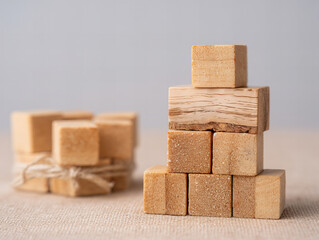 Wooden building blocks arranged in a creative tower on a neutral background with bundled pieces nearby