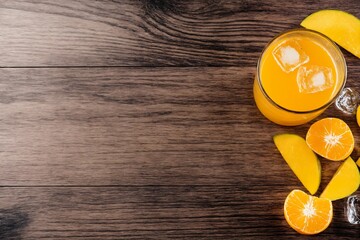 Mango juice glass with ice and fresh fruits on wooden table background
