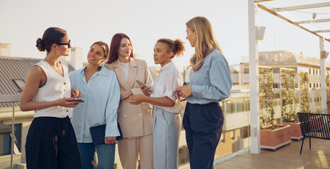 A group of professional women on a rooftop engages in meaningful conversation, showing empowerment