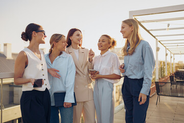 A group of women engaging in lively and cheerful conversation on a vibrant rooftop setting