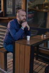 Man sitting alone at a wooden table enjoying coffee in a cozy outdoor cafe during golden hour