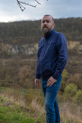 Man stands on a hillside overlooking a scenic valley during a cloudy day in nature