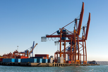 Cranes waiting to unload commercial goods from ships in port