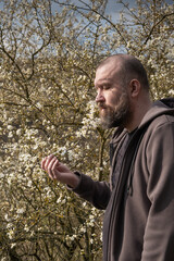 Man enjoying nature while standing among blooming flowers in early spring sunlight