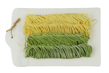 Egg and spinach tagliatelle on ceramic board isolated on white background. Types of uncooked pasta....