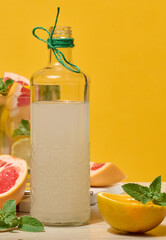 Fresh citrus drink with lemon, grapefruit, and mint in a glass with ice cubes. Surrounded by fresh...
