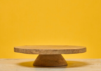 Wooden round podium on wooden table, on bright yellow background. Place for demonstration of...