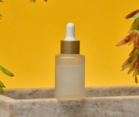 Glass frosted bottle with white pipette on marble stand, cosmetic product