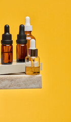 Cosmetic bottles with pipettes on a stone stand. Stylish composition for skin care, oils and serums...