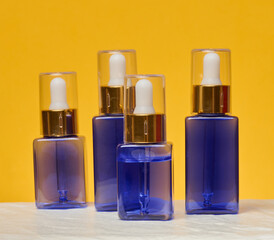 Transparent square blue bottles with gold caps and white pipettes