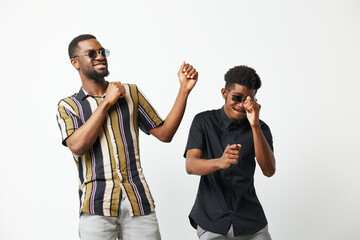 Joyful black men dancing together in stylish sunglasses, showcasing friendship and celebration....
