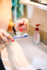 Woman holding toothbrush while standing in the bathroom in the morning