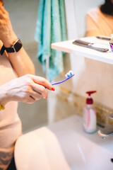Woman holding toothbrush while standing in the bathroom in the morning