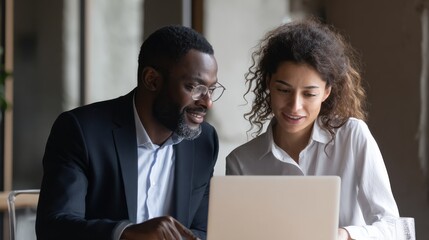 Businessman indian executive manager ceo talking to female African American coworker, using laptop. Diverse multicultural professional partners group discussing business plan at board room meeting.,