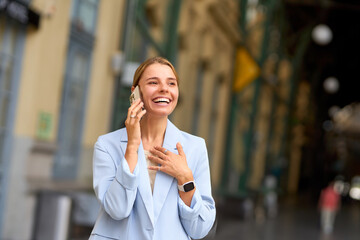 A Smiling Woman Engaged in a Conversation Over the Phone While Outdoors in Daylight