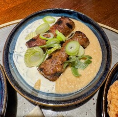 Meat kebabs and hummus garnished with spring onions
