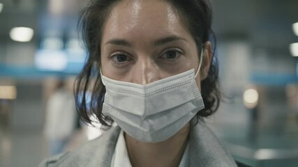 Woman in face mask stands in airport during covid-19 pandemic - Powered by Adobe