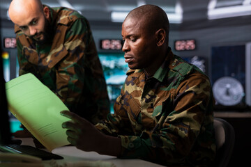 Military officer reading intel documents to organize mission activities. Intelligence specialist...
