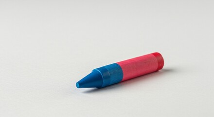 A stubby crayon in two colors, blue at the pointed end and red at the rounded end, lies on a white surface.