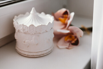 Arrangement of pink orchids, elegantly displayed next to a white decorative carousel. Delicate...