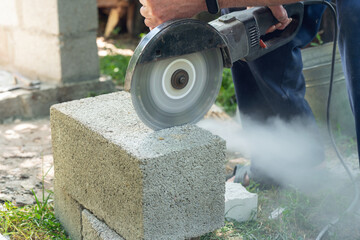 Worker cutting cinder block with angle grinder