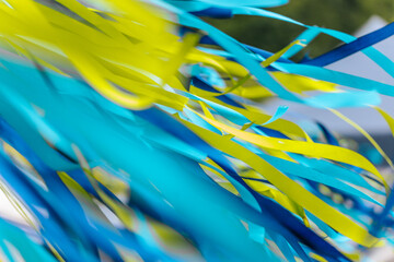 Close-up of dynamic blue and yellow ribbons fluttering in the wind at an outdoor event, creating a...