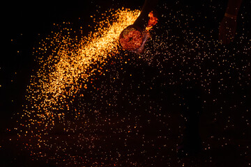 Thousands of glowing orange sparks cascade against a black background, creating a fiery and dynamic...
