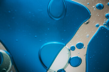 Vibrant green droplet encased in a blue fluid form, set against a neutral background with tiny...