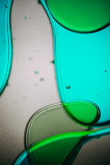 Vibrant green droplet encased in a blue fluid form, set against a neutral background with tiny...