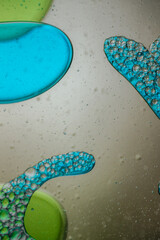Vibrant green droplet encased in a blue fluid form, set against a neutral background with tiny...