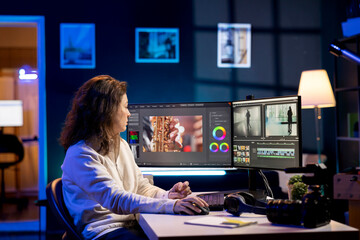 Video producer adds sound effects to film montage, working in studio. Videographer using headphones...