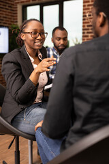 Female business consultant with glasses provides financial advice to black man in brick wall office. African american woman manager discusses a company project while questioning her male employee.