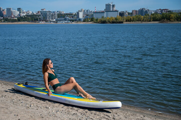 Caucasian woman posing on a SUP board. Summer sport.