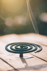 Smoldering mosquito coil in summer garden on wooden table, insect protection