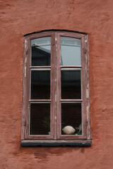 Photo of an old window with red shutters on a historic house. Highlights the charming architecture and vibrant details, perfect for travel, architecture, and heritage projects.