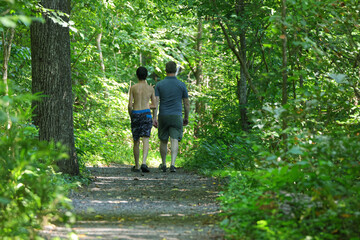 Father and son walking down dark path in the woods. 