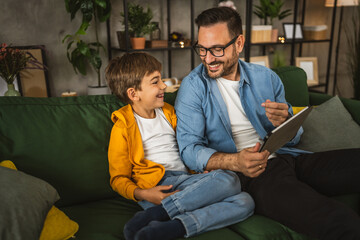 Father with eyeglasses and son use tablet for homework browse internet