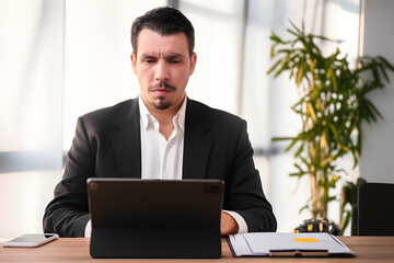 Focused businessman working on a tablet in an office setting.