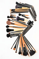 An assortment of makeup brushes arranged in a spiral pattern against a white background.