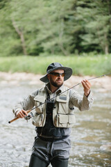 Fisherman catching trout in river, fly fishing in mountain stream