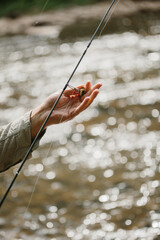 Fisherman placing bait on hook for trout fishing in river