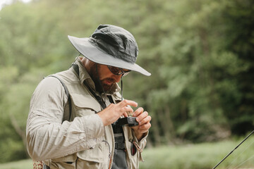 Fisherman adjusting camera settings during trout fishing trip