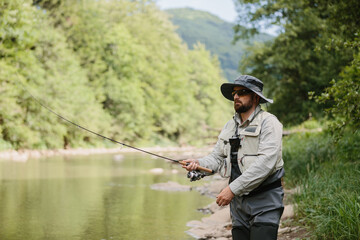 Fisherman casting line in river, enjoying trout fishing in nature