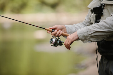 Fisherman holding fishing rod, trout fishing in river