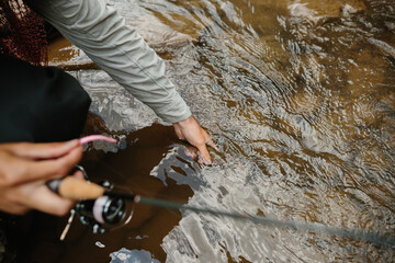 Fisherman checking water temperature while trout fishing