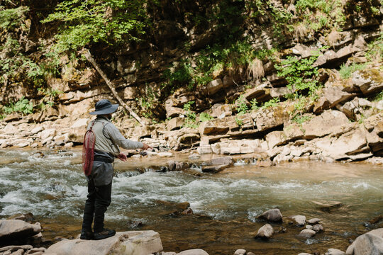Fisherman casting line in a pristine mountain river for trout fishing - Powered by Adobe