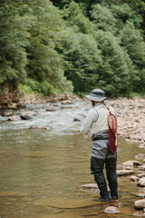 Fisherman with fishing rod and net fishing in river