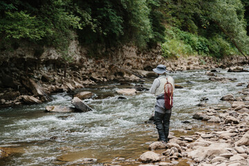 Fisherman catching trout in wild river